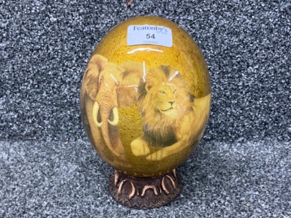 An ostrich egg in n stand with African animals