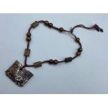 An Asian brown jade necklace with heavily hand-carved pendant