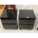 A pair of black glass bedside drawers