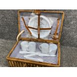 Vintage wicker picnic hamper containing plastic cups, plates & cutlery