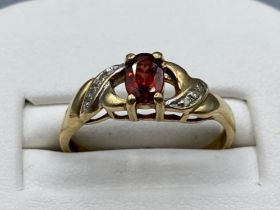 Ladies 9ct yellow gold garnet and diamond ring, comprising of a oval garnet stone set in the