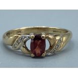 Ladies 9ct yellow gold garnet and diamond ring, comprising of a oval garnet stone set in the