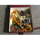 A box of mixed costume jewellery includes bangles beaded necklaces etc