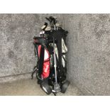 2 golf bags containing various different clubs together with a golf trolley