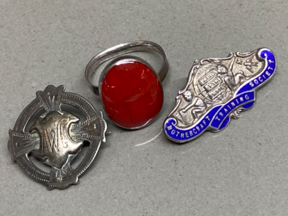 2 hallmarked silver badges including mother craft training society & AWG, together with a silver red