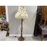 Heavily carved oak based pedestal standard lamp with fringed floral patterned shade