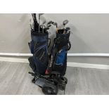 2 golf bags containing various different clubs together with a golf trolley