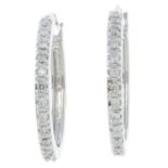 A pair of brilliant-cut diamond hoop earrings.