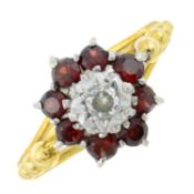 A brilliant-cut diamond and garnet cluster ring, with textured shoulders.