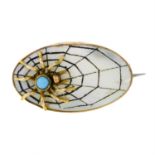 A late Victorian mother-of-pearl spider and web brooch, with green gem highlight.