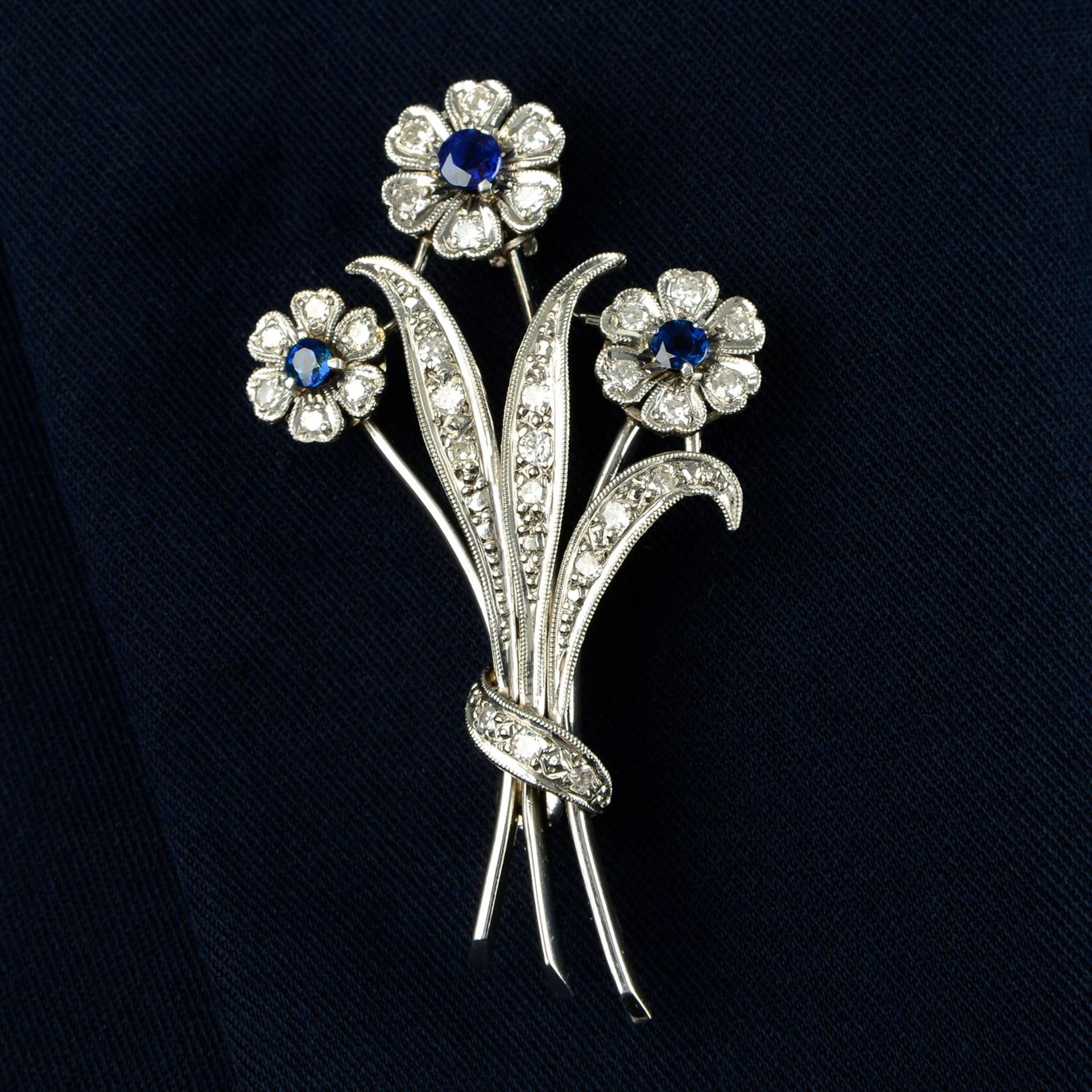 A mid 20th century 18ct gold vari-cut diamond and sapphire floral spray brooch.