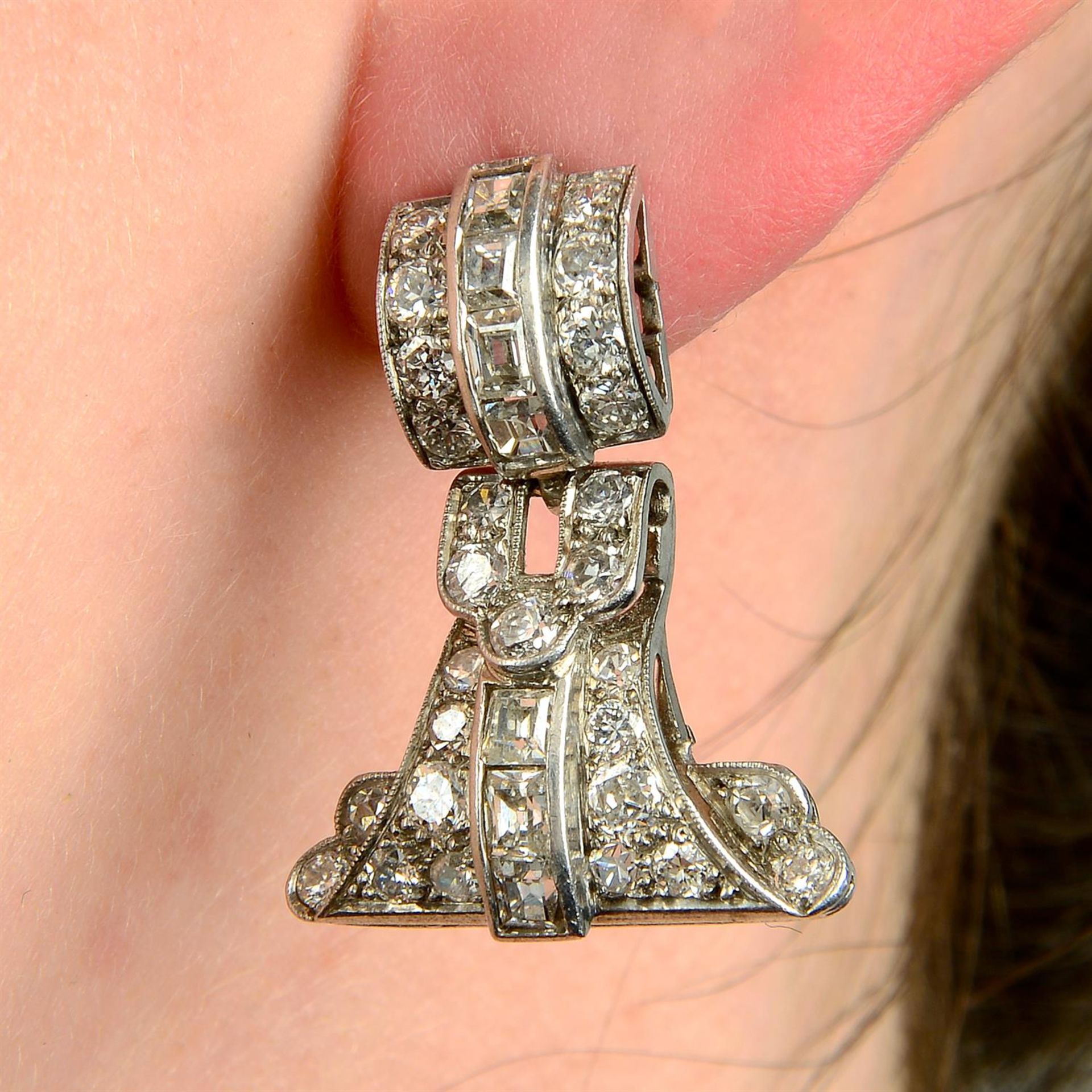 A pair of brilliant and baguette-cut diamond earrings.