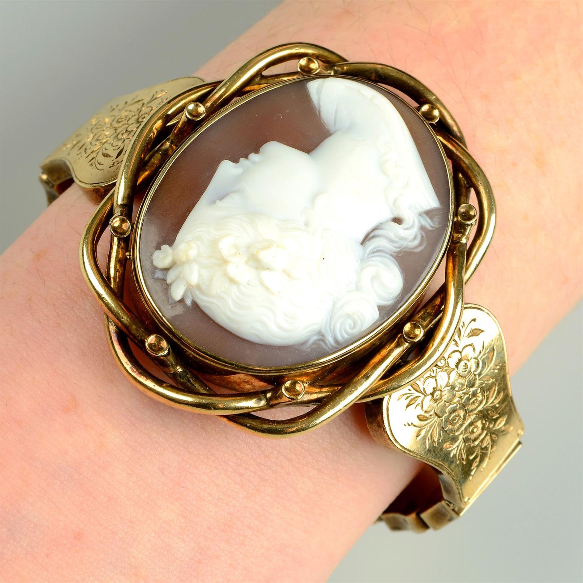 A late 19th century gold shell cameo bracelet, depicting Flora, with floral engraved sides.