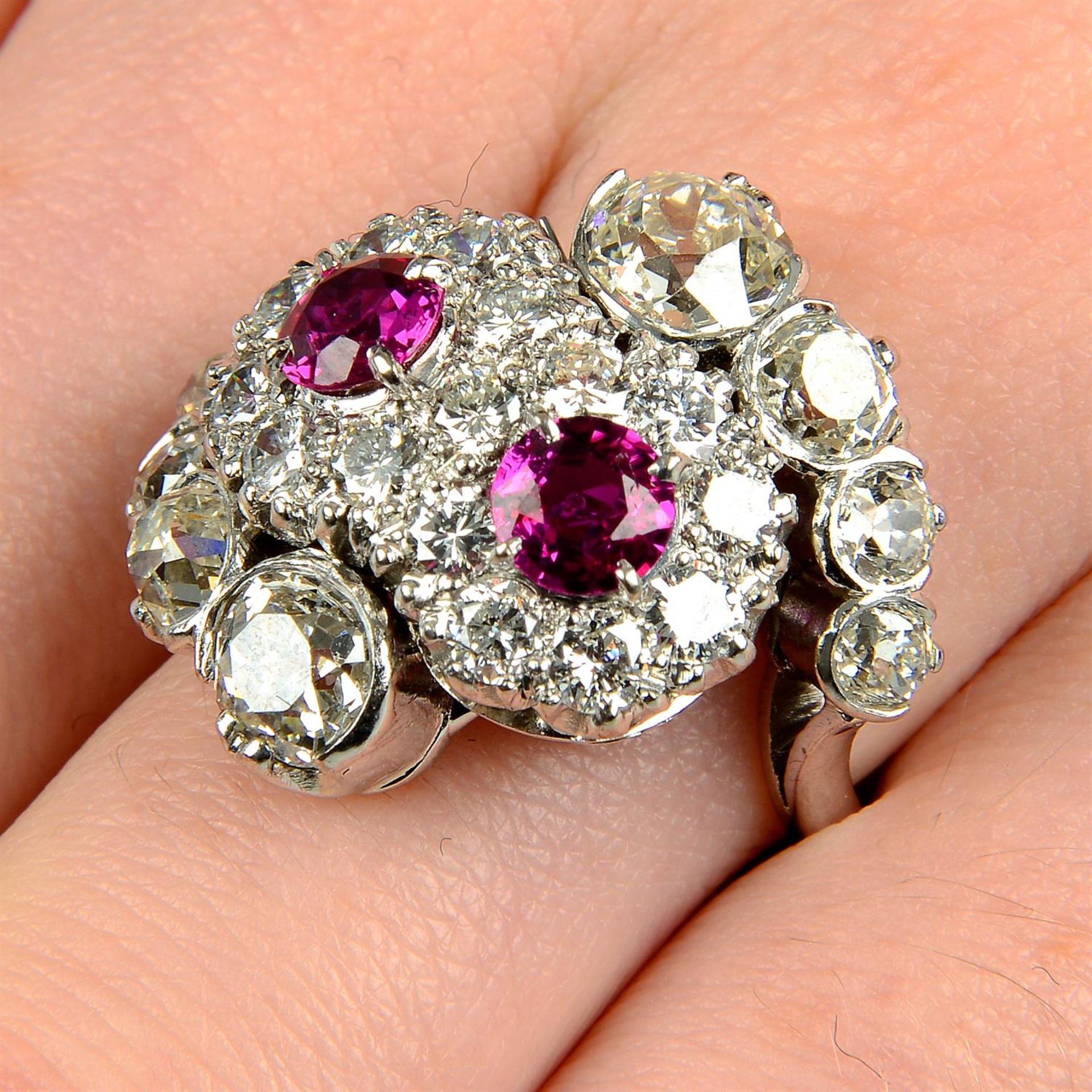 A ruby and brilliant-cut diamond double cluster ring, with graduated old-cut diamond asymmetric