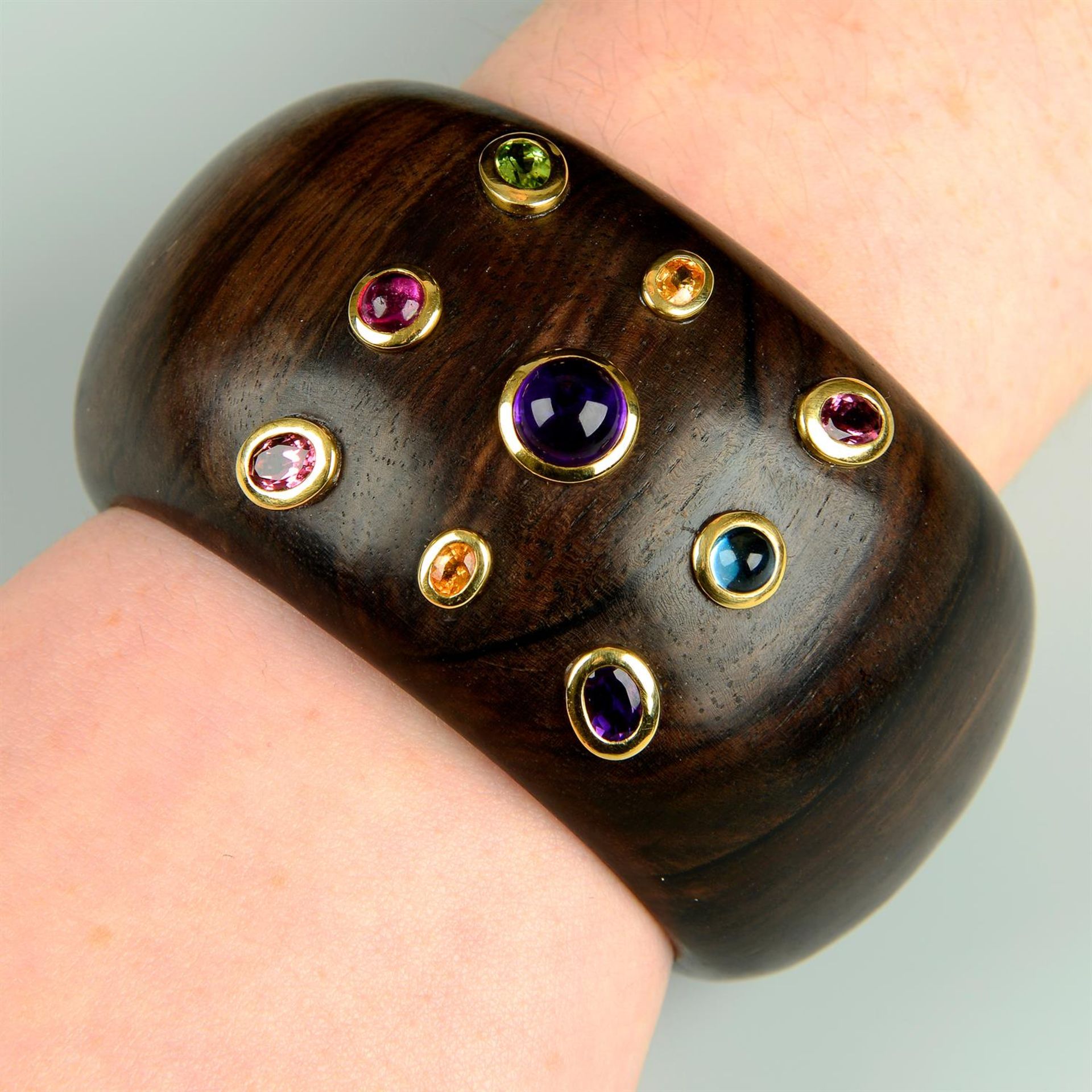 A jacaranda cuff bangle set with amethyst, blue and orange topaz, pink tourmaline and peridot.