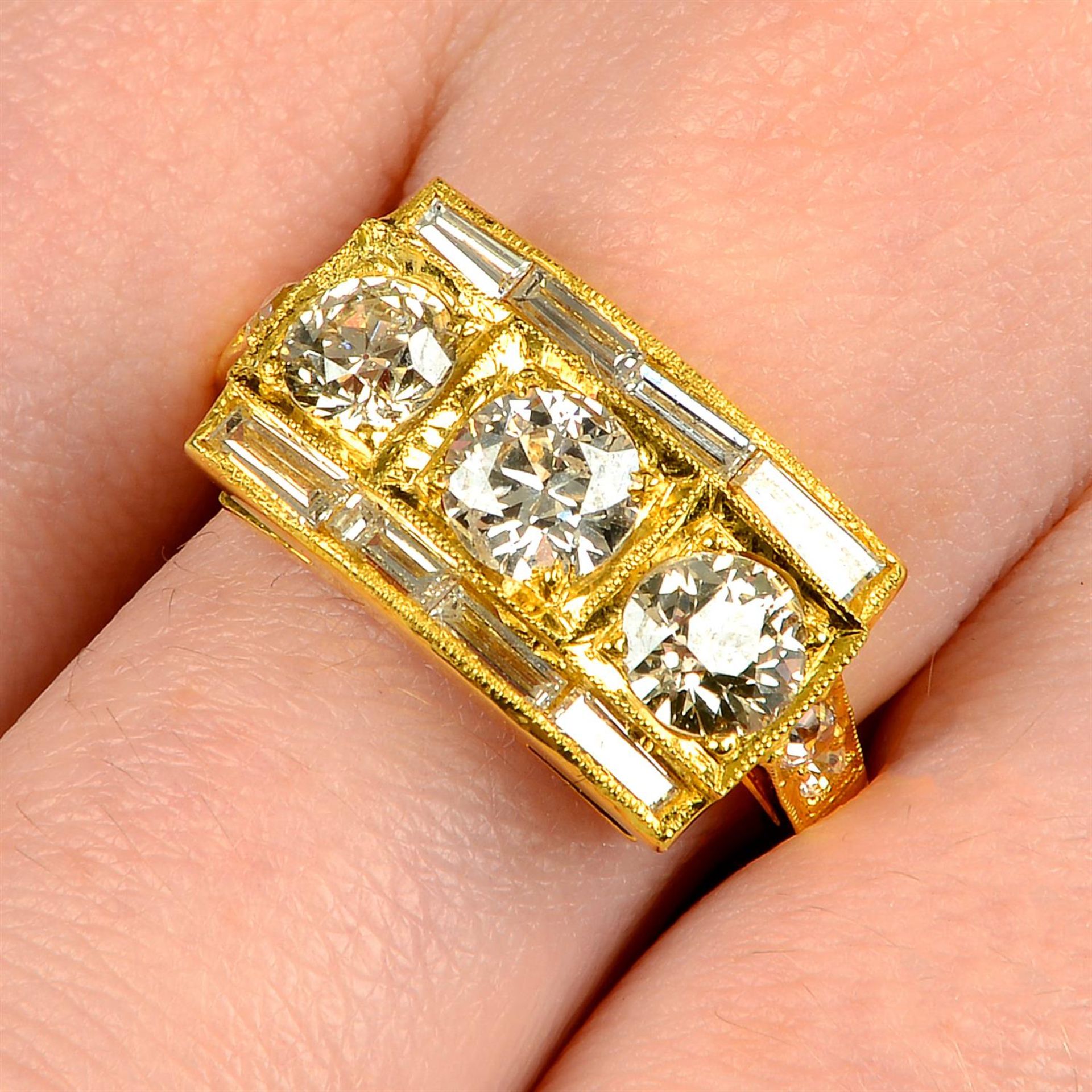 A circular-cut diamond three-stone ring, with vari-cut diamond sides and shoulders.