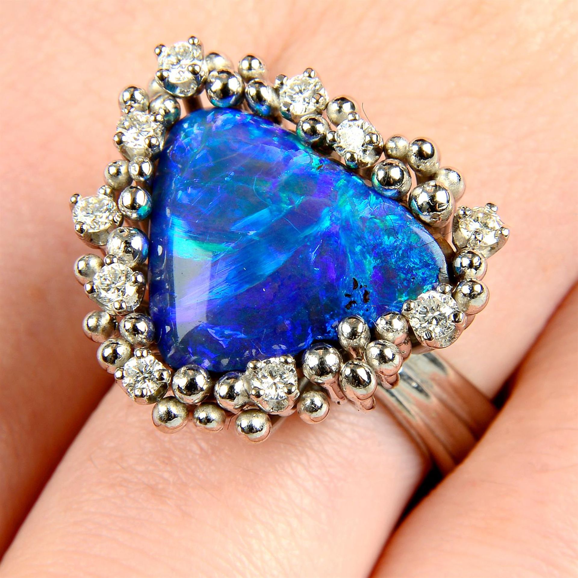 A boulder opal ring, with brilliant-cut diamond and bead surround, by Grima.