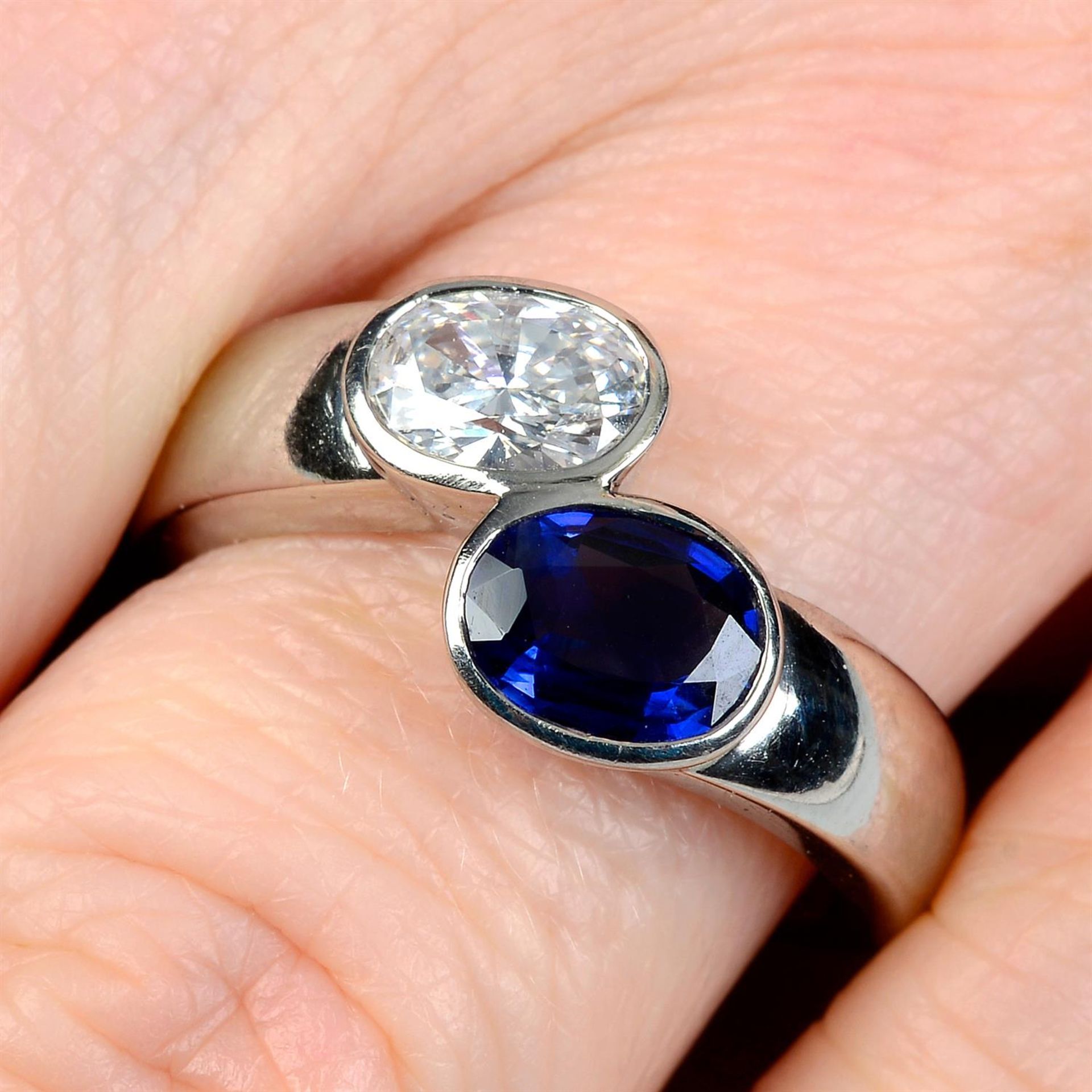 A platinum, oval-shape diamond and sapphire 'Toi et Moi' crossover ring.