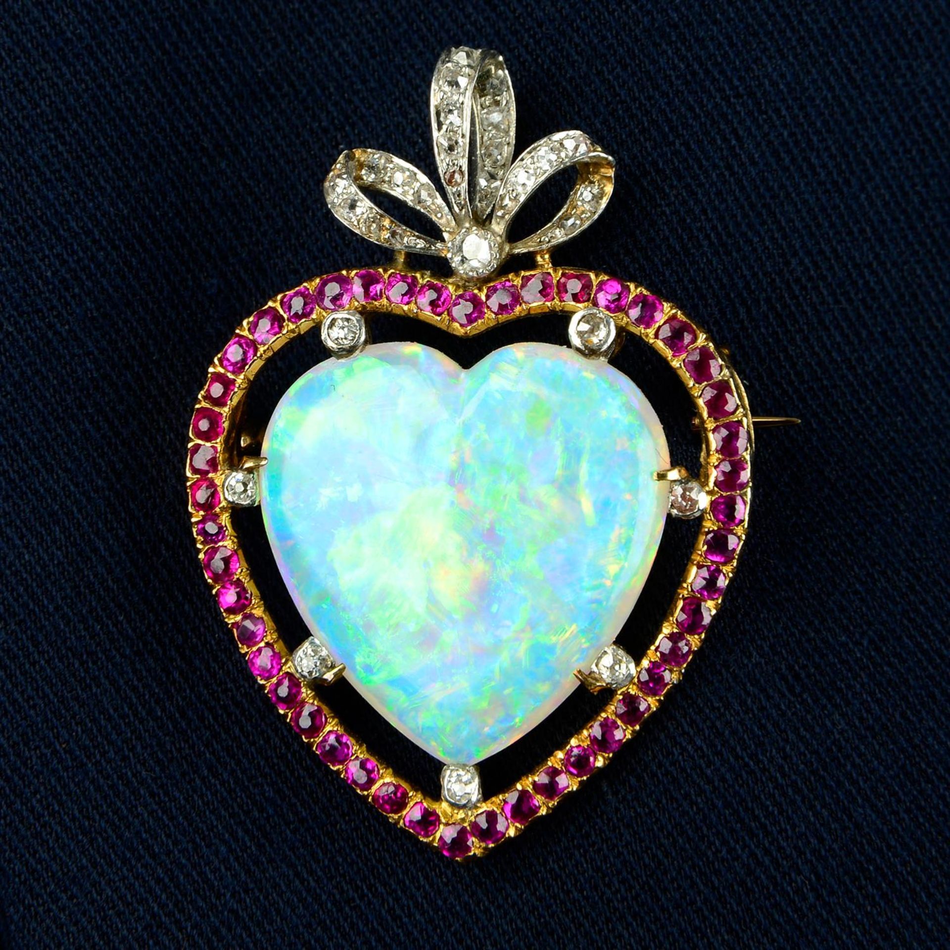 An Edwardian platinum and 18ct gold opal heart cabochon, ruby and diamond bow brooch.