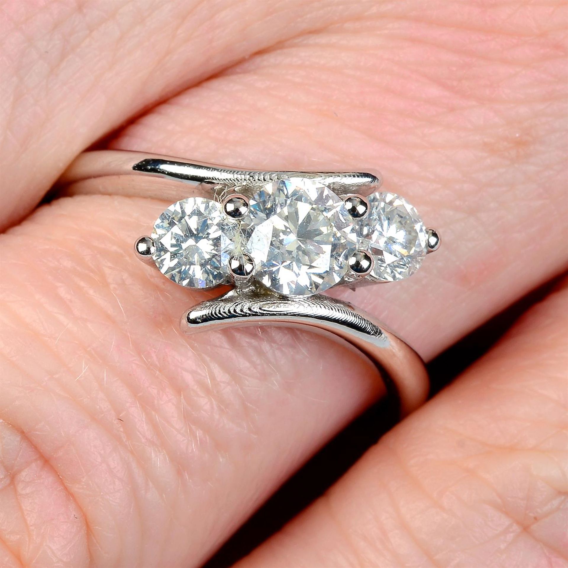 A graduated brilliant-cut diamond three-stone ring, with asymmetric sides.