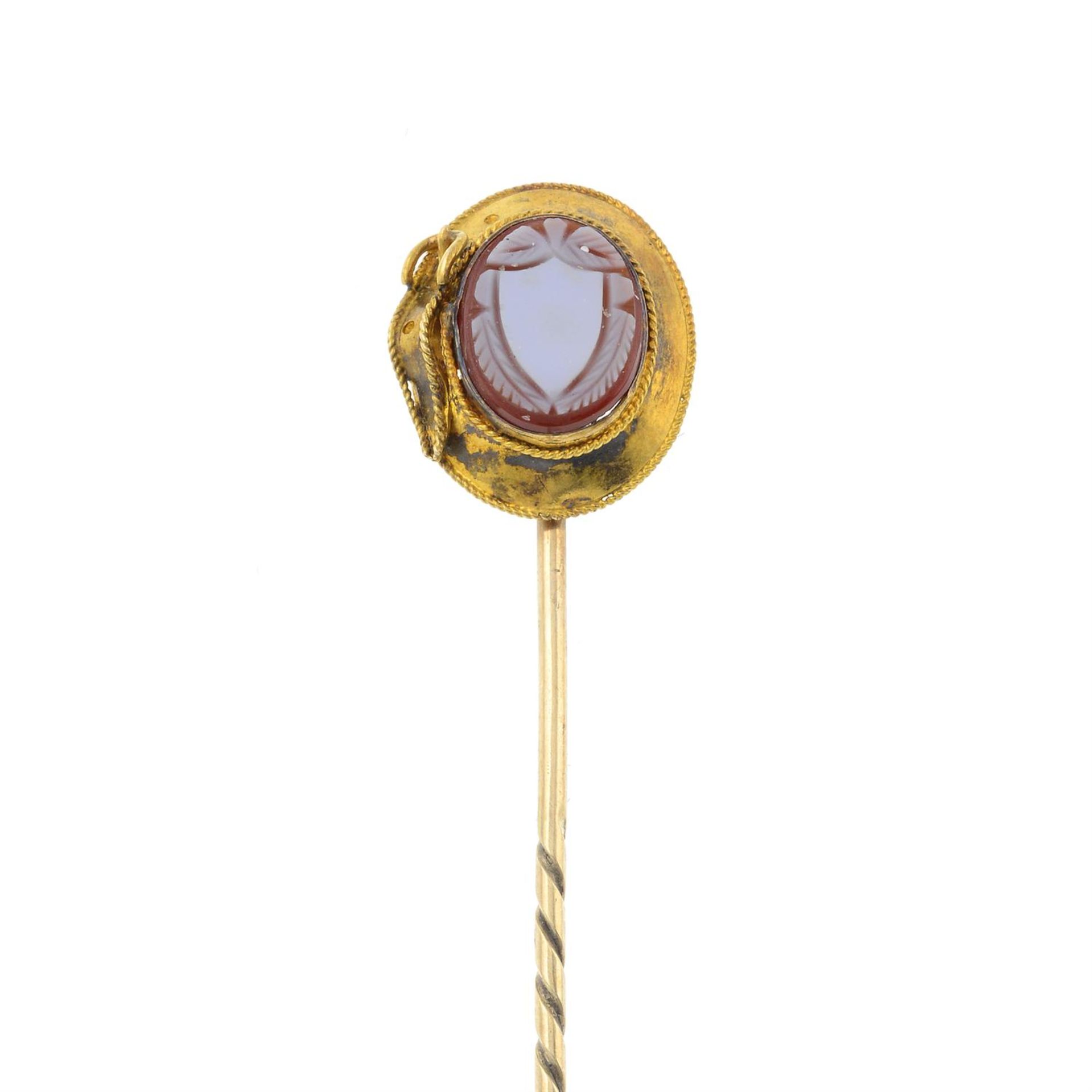 A carved carnelian stickpin, depicting a belt.