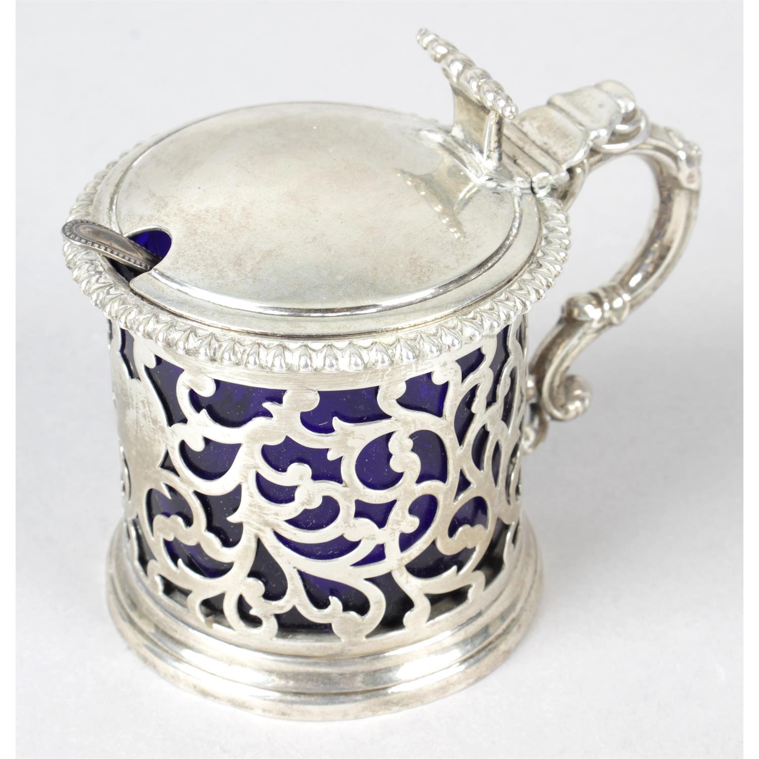 A Victorian pierced silver mustard pot, together with an early George V plainer example. (2).