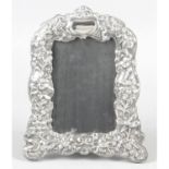 A modern Britannia silver mounted photograph frame with floral embossed decoration.