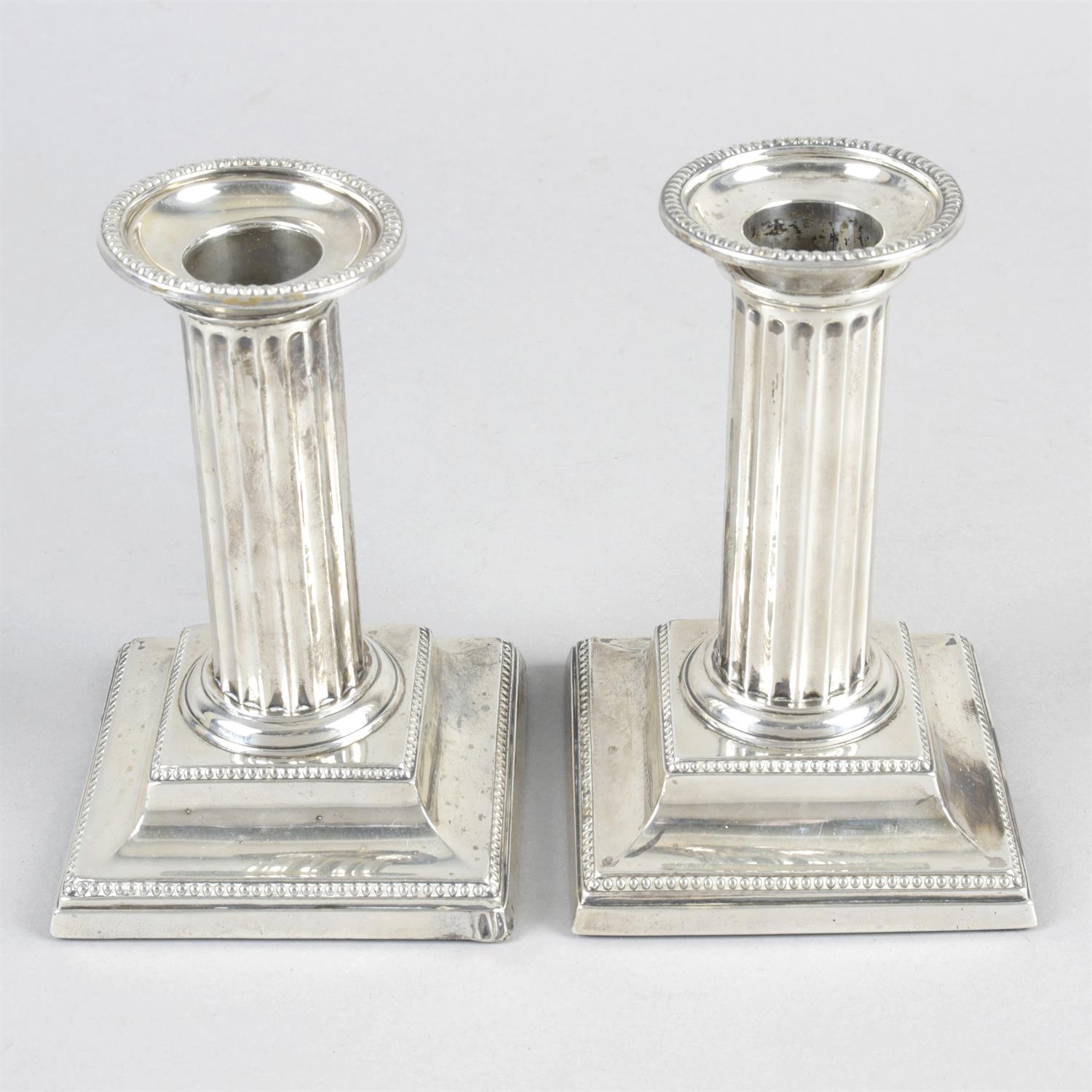 A pair of late Victorian silver mounted small candlesticks. (filled).