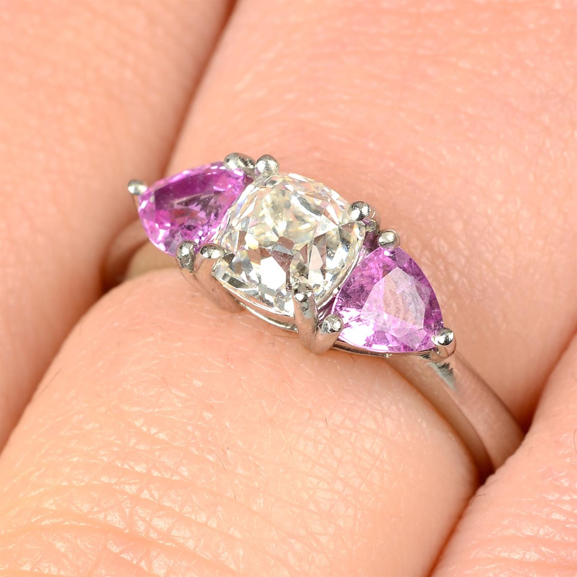 A platinum old-cut diamond and triangular-shape pink sapphire three-stone ring.