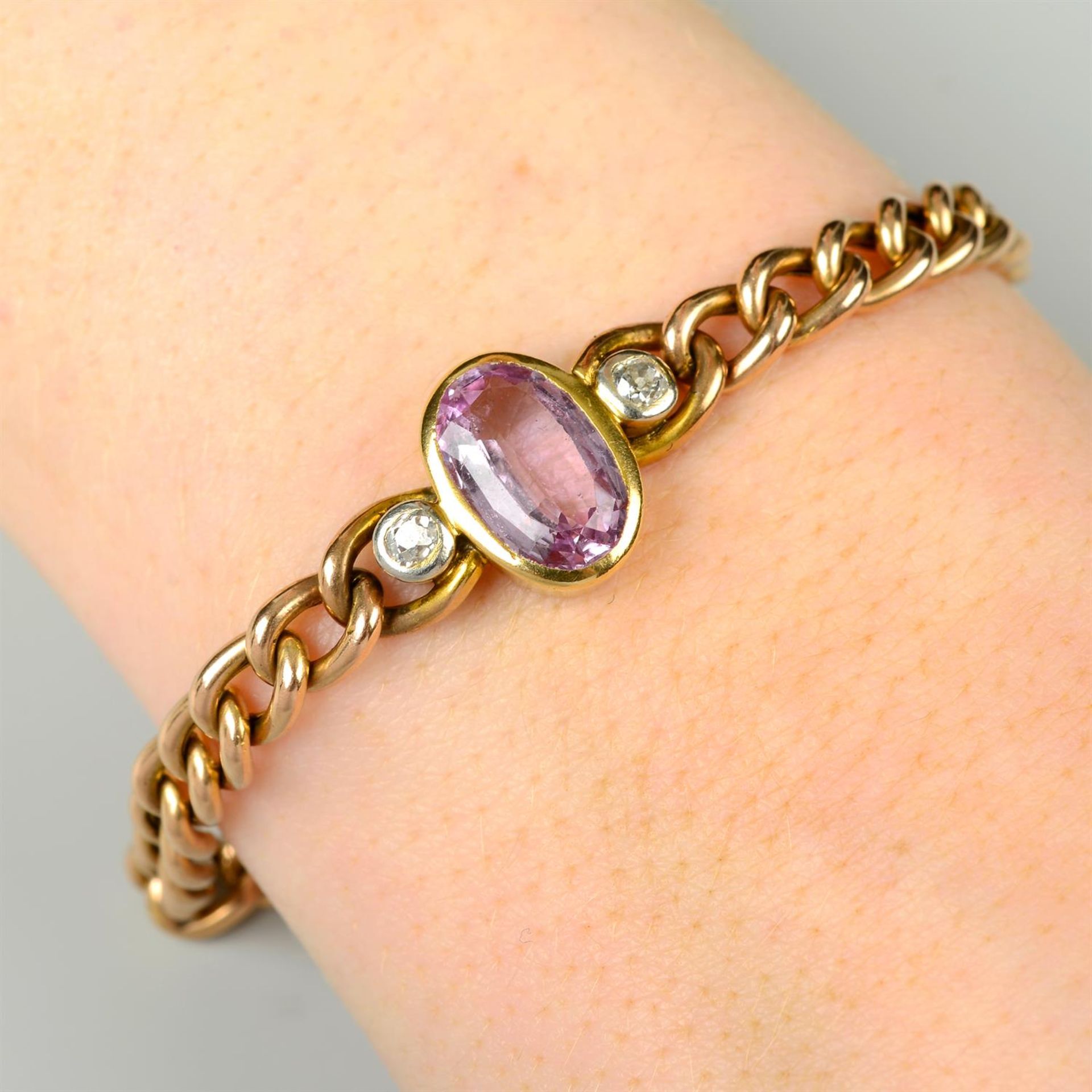 An early 20th century gold curb-link bracelet, with pink topaz and old-cut diamond sides inset.