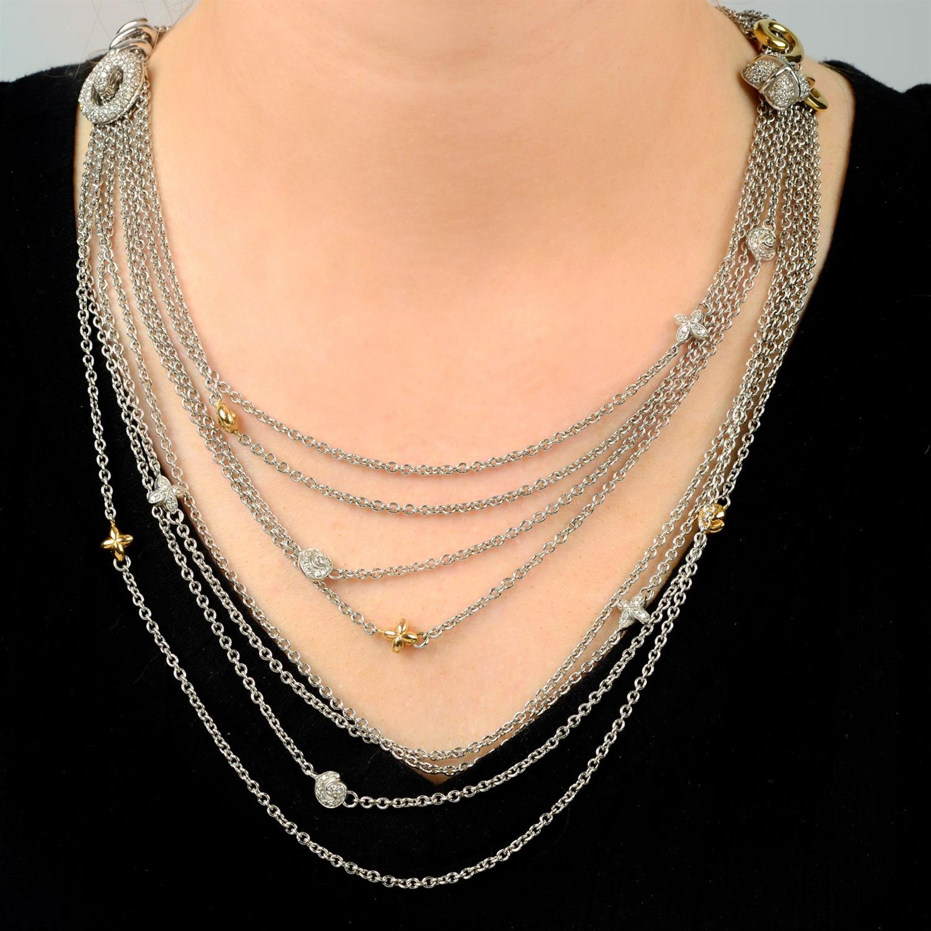 A multi-strand necklace, gathered at diamond and polished scroll and quatrefoil spacers,