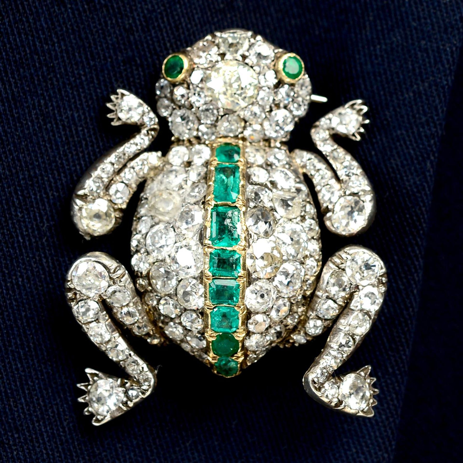 An early 20th century vari-cut diamond and emerald frog brooch.