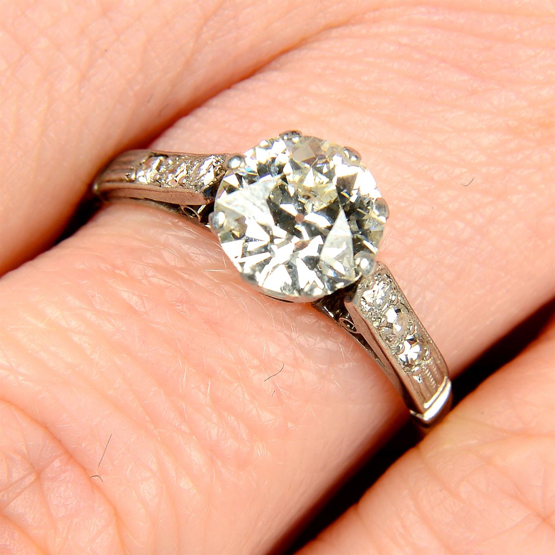 A mid 20th century platinum old-cut diamond single-stone ring, with vari-cut diamond line sides.