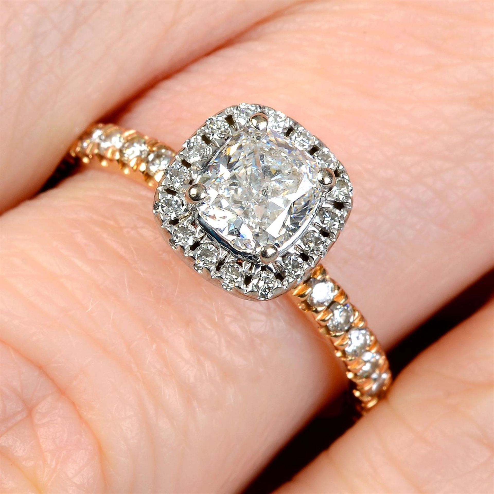 A cushion-shape diamond single-stone ring, with brilliant-cut diamond surround and sides.