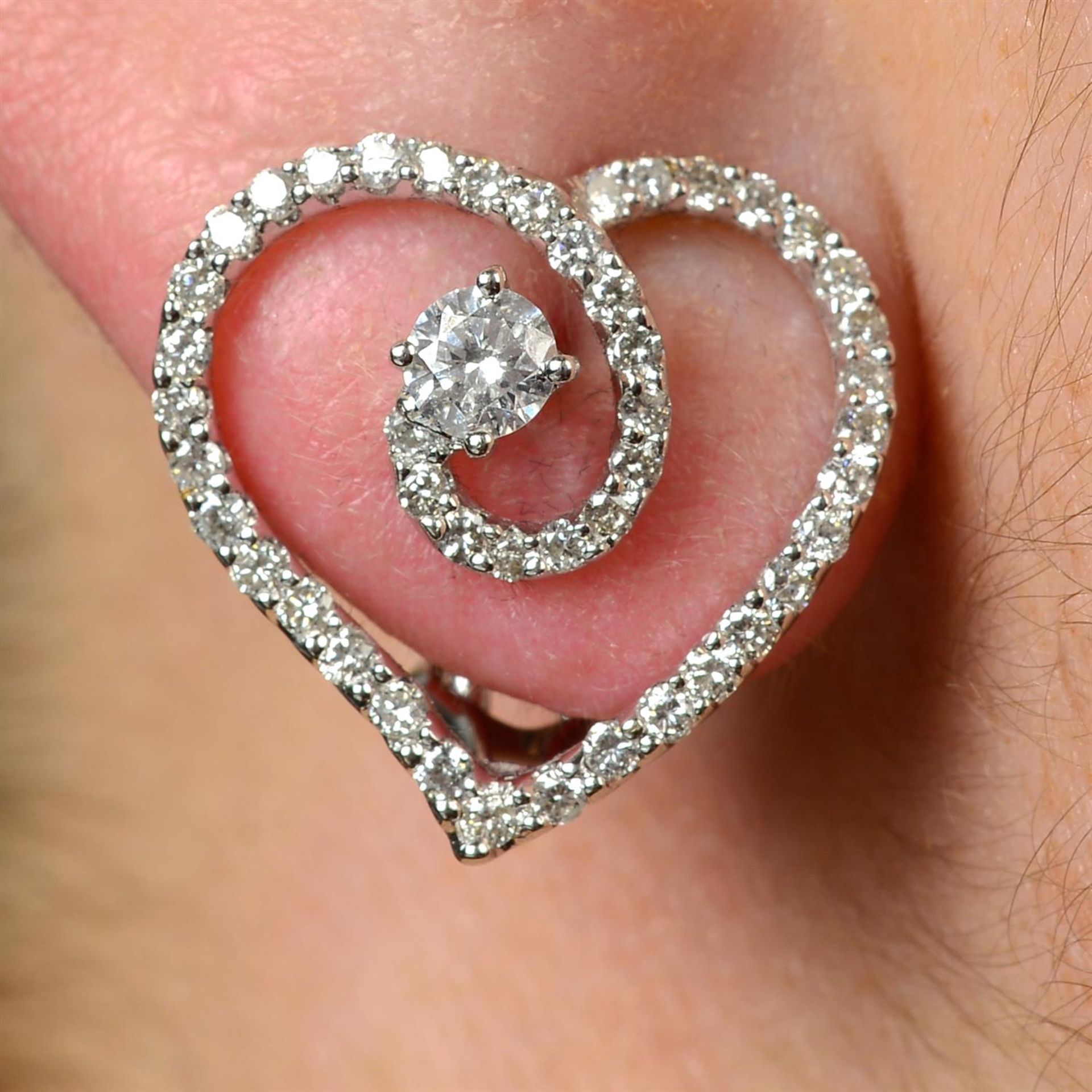 A pair of brilliant-cut diamond heart earrings.