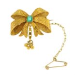 A late 19th century gold textured bow brooch, with emerald highlight.