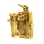 A 1960s 9ct gold sewing machine charm, hinged to reveal a sewing kit.