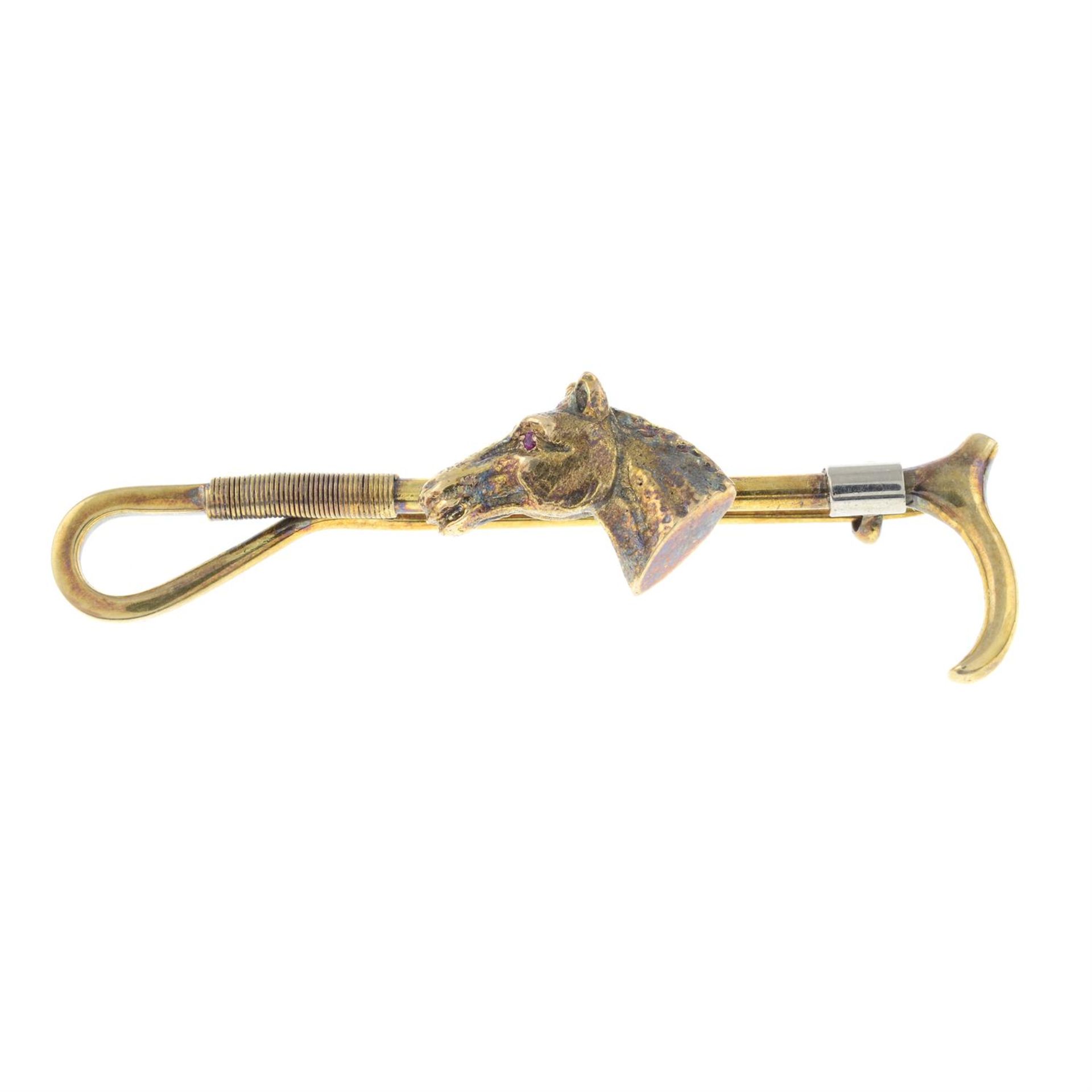 A 1970's 9ct gold horse and riding crop bar brooch, with ruby eye highlights.
