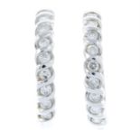 A pair of brilliant-cut diamond hoop earrings.