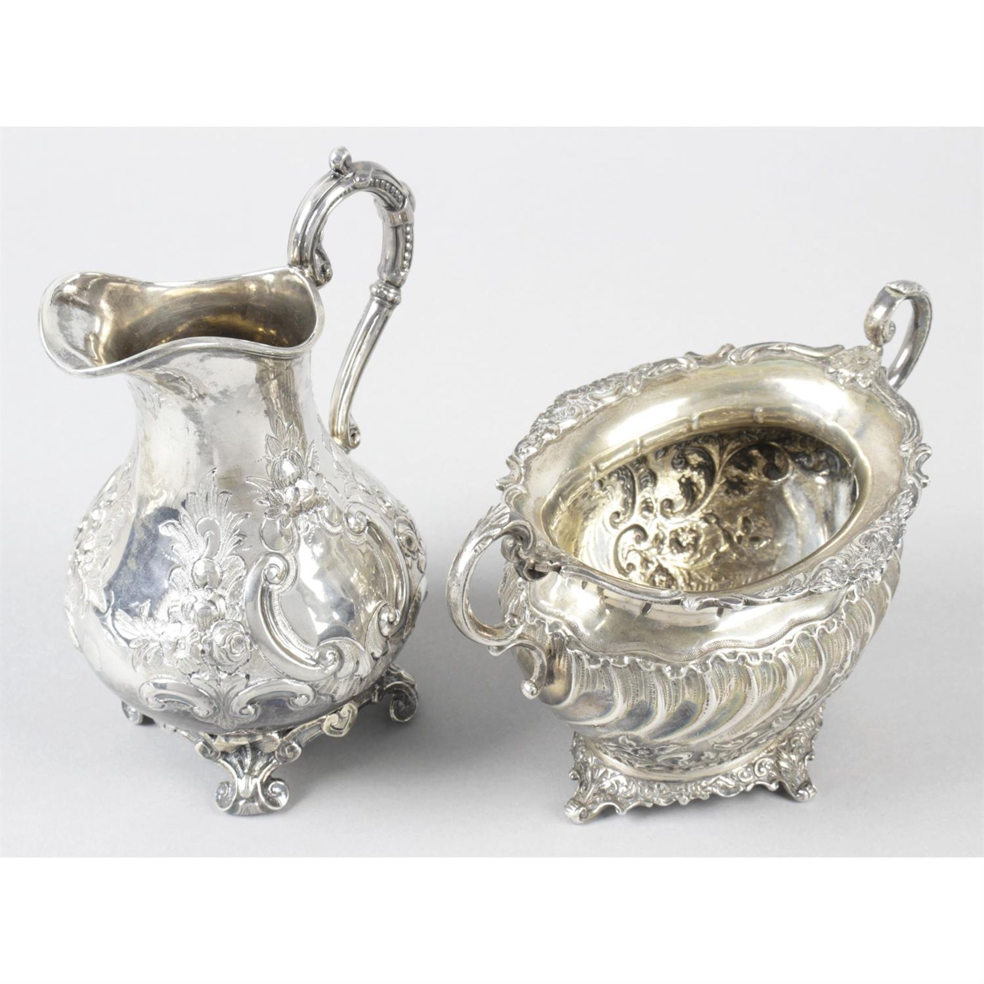 A Victorian embossed silver cream jug, together with a later twin-handled sugar bowl. (2).