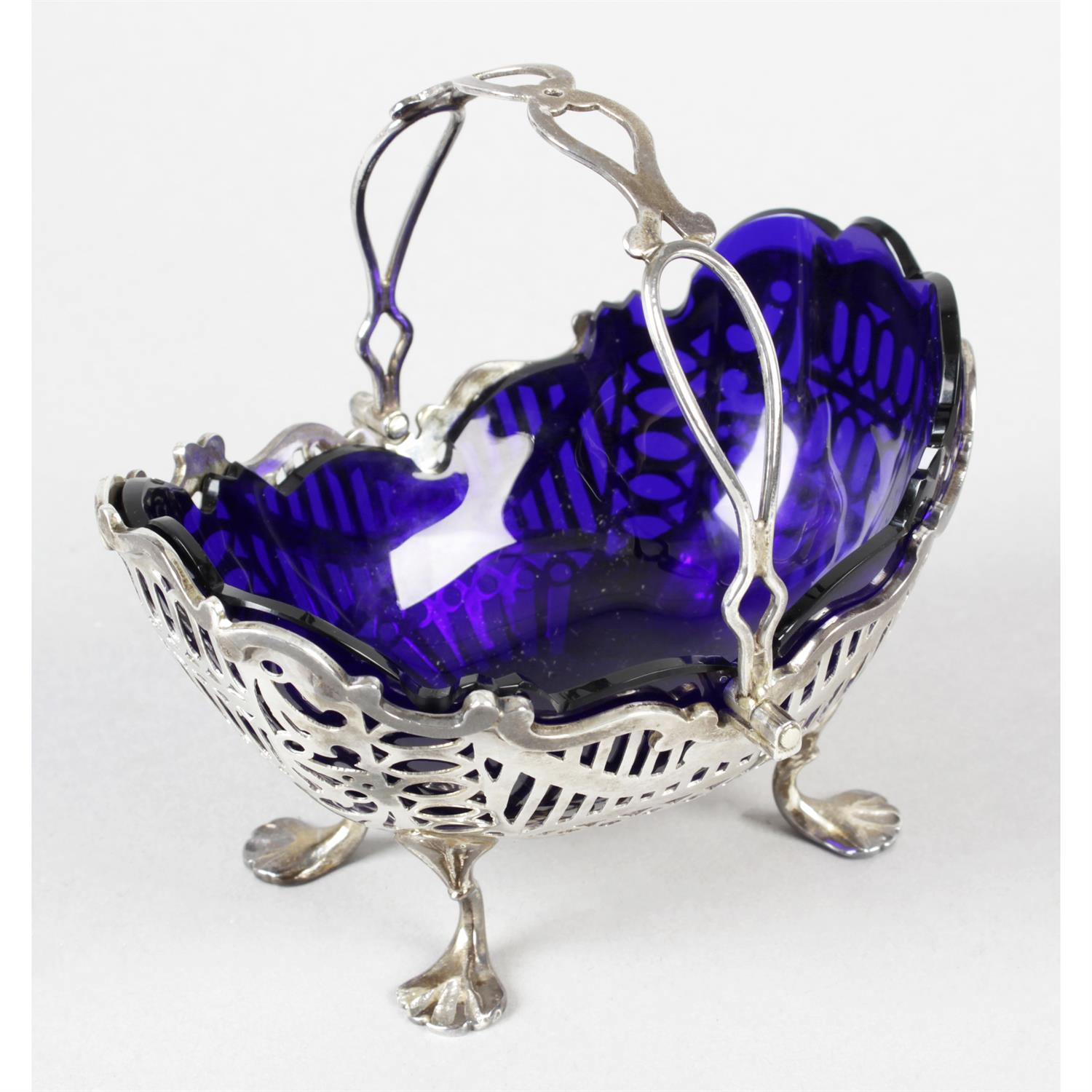 A late Victorian silver sugar basket with blue glass liner.