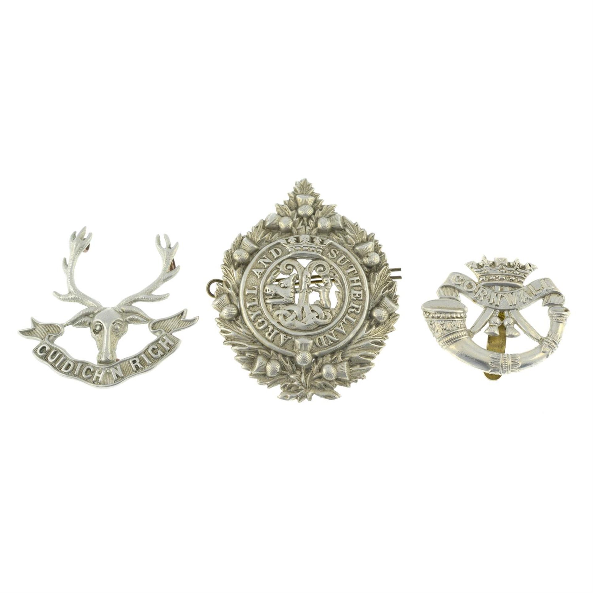 A selection of assorted cap badges, etc.