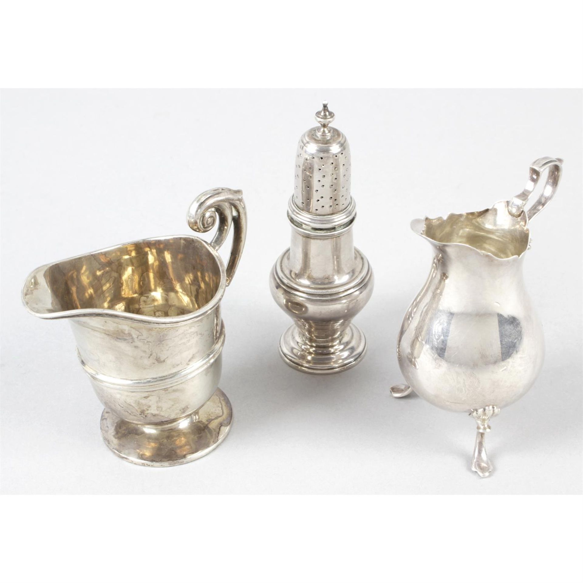 Two late Victorian silver cream jugs, together with a 1920's silver pepperette. (3).