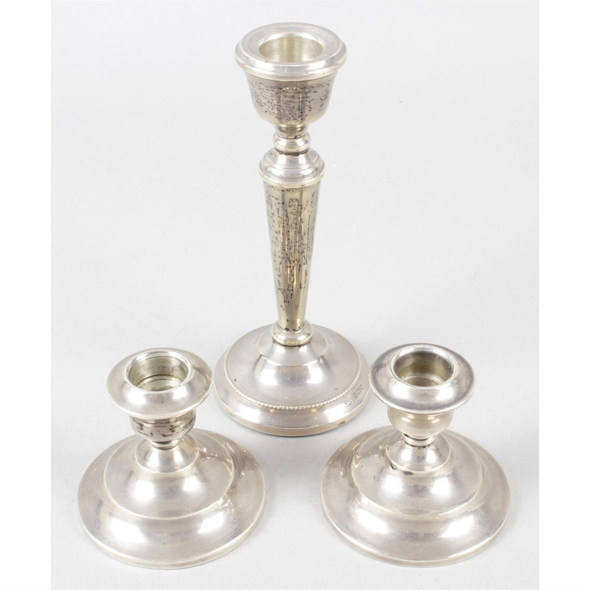 A pair of mid-20th century silver dwarf candlesticks, together with a later silver single