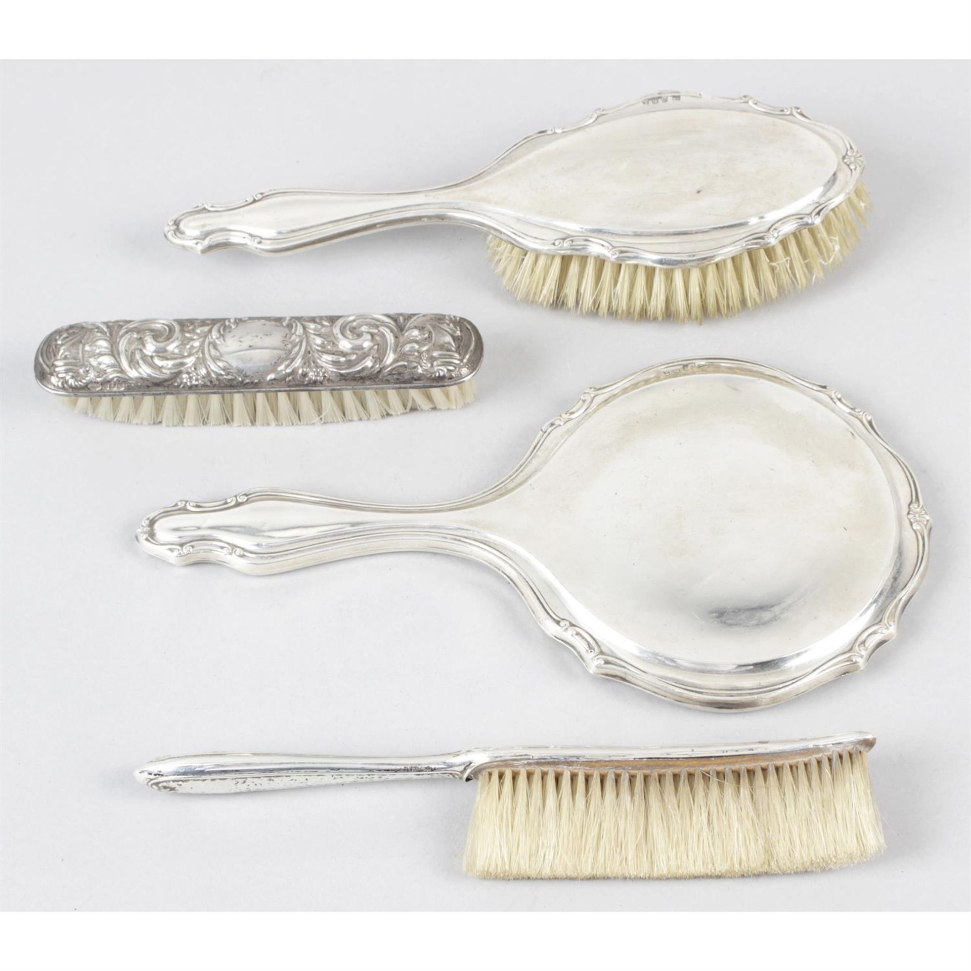 A silver mounted brush and hand-held mirror set, together with two smaller brushes. (4)