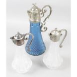A pair of clear glass claret jugs with plated mounts, together with a blue glass example. (3).