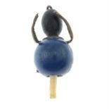 A wooden bead with suspended celluloid legs figure charm.