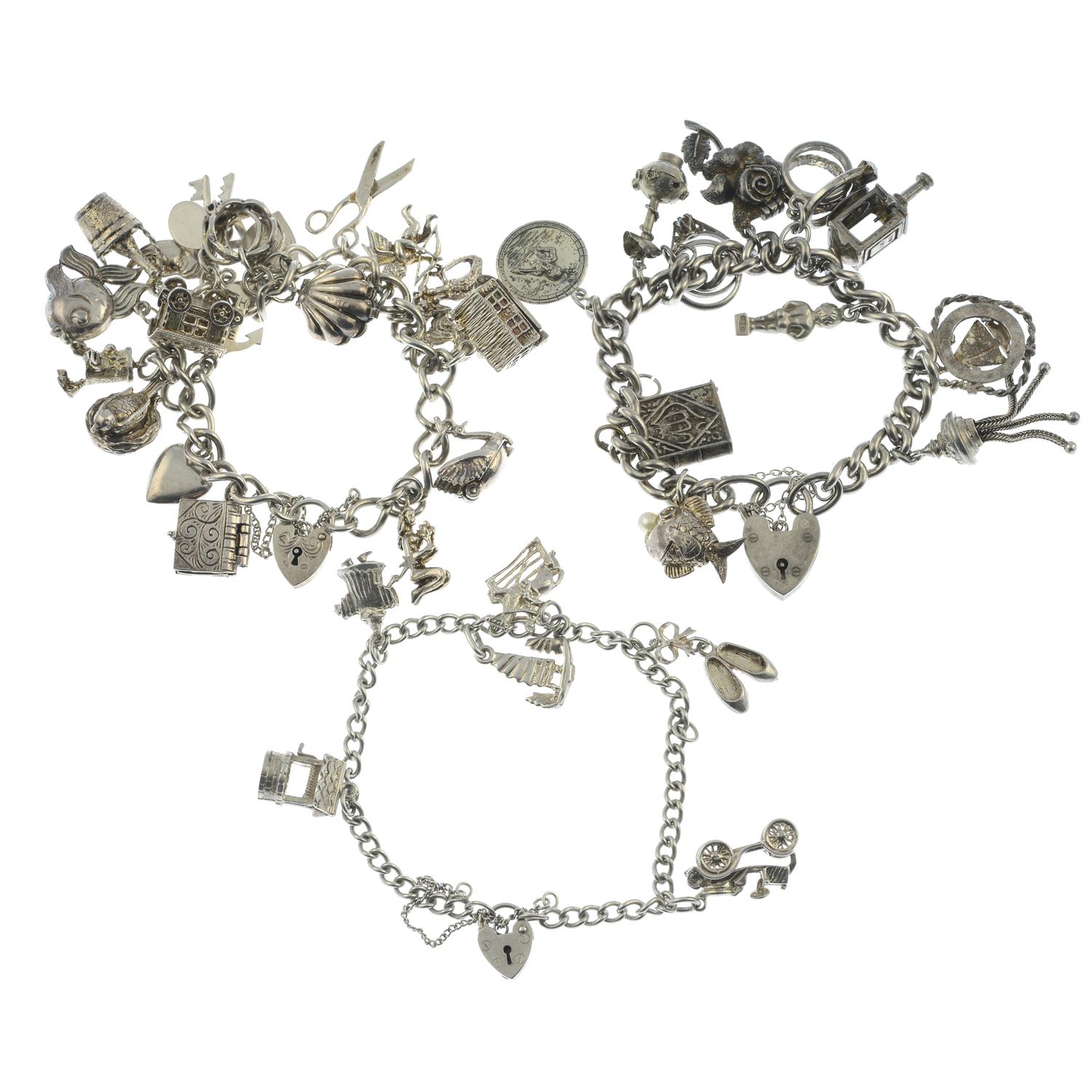 Two silver charm bracelets and a further charm bracelet, with a variety of charms.