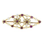 An early 20th century ruby and split pearl floral openwork panel brooch.