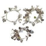 Three silver charm bracelets, suspending many charms.
